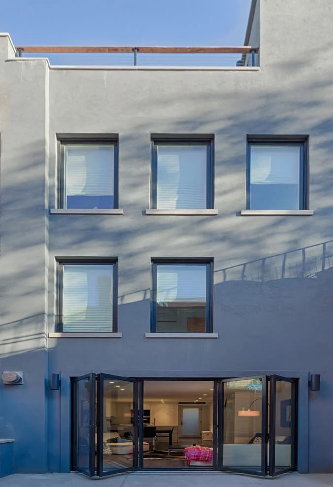 Rear facade of a renovated Brooklyn townhouse with new windows and folding garden doors, by Grandeur Hills Group